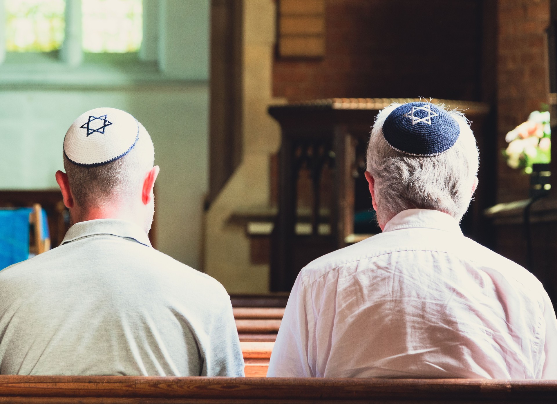 Jewish men sitting together and praying inside synagogue